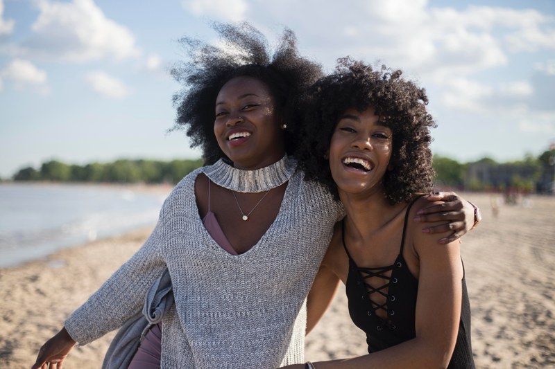 Two African American siblings taking a picture together at the beach.